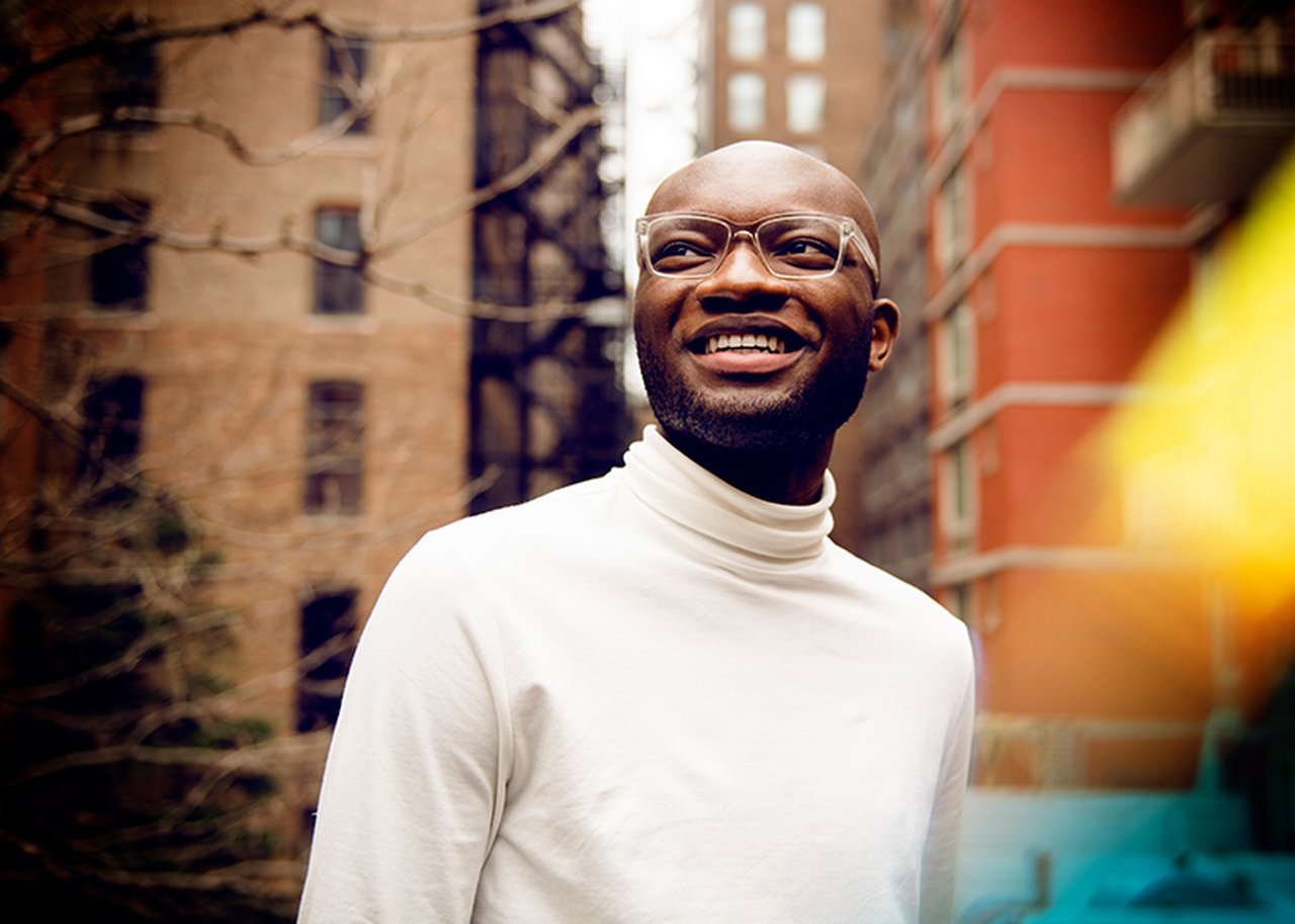 Kofi smiles in front of two apartment blocks