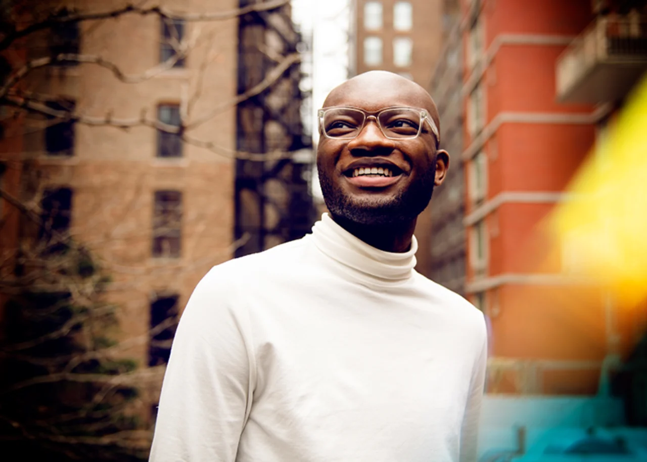Kofi smiles in front of two apartment blocks