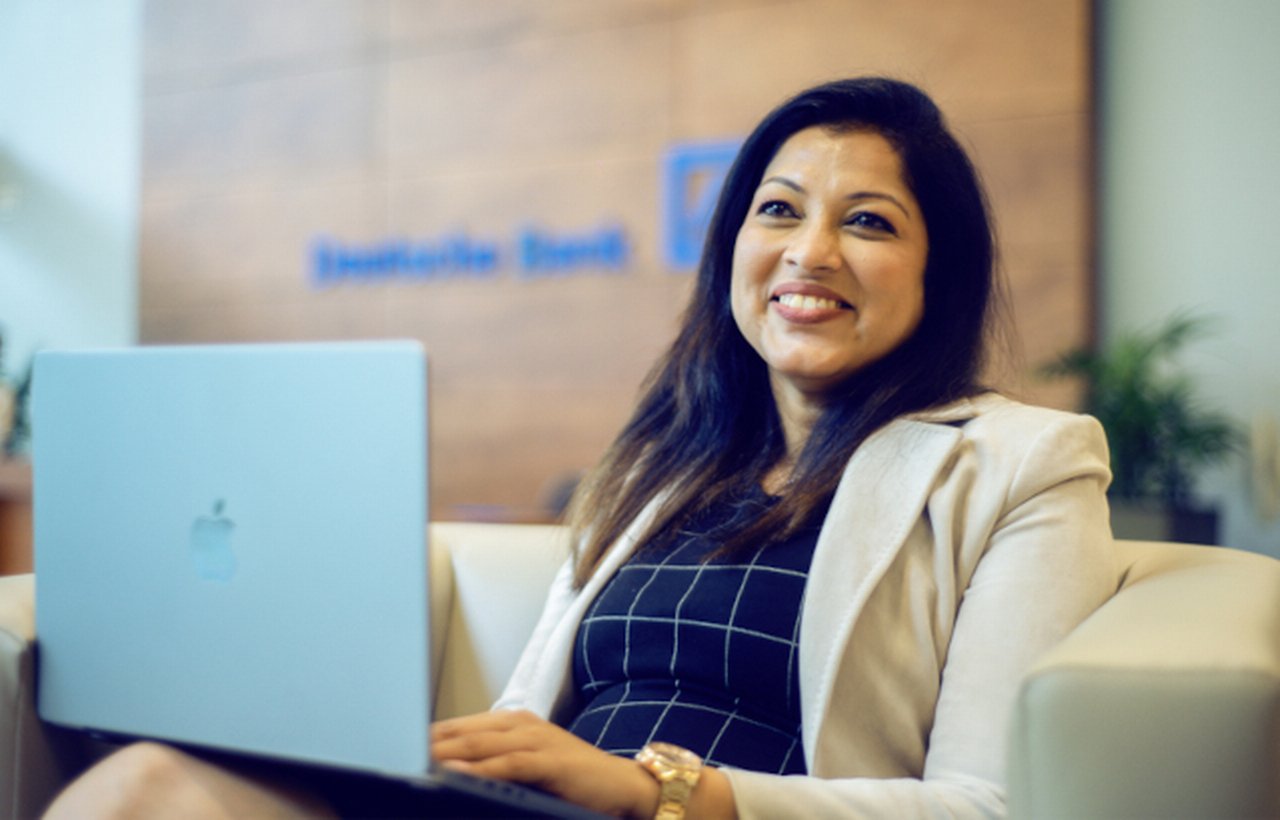 Woman sits in deutsche bank lobby with her laptop