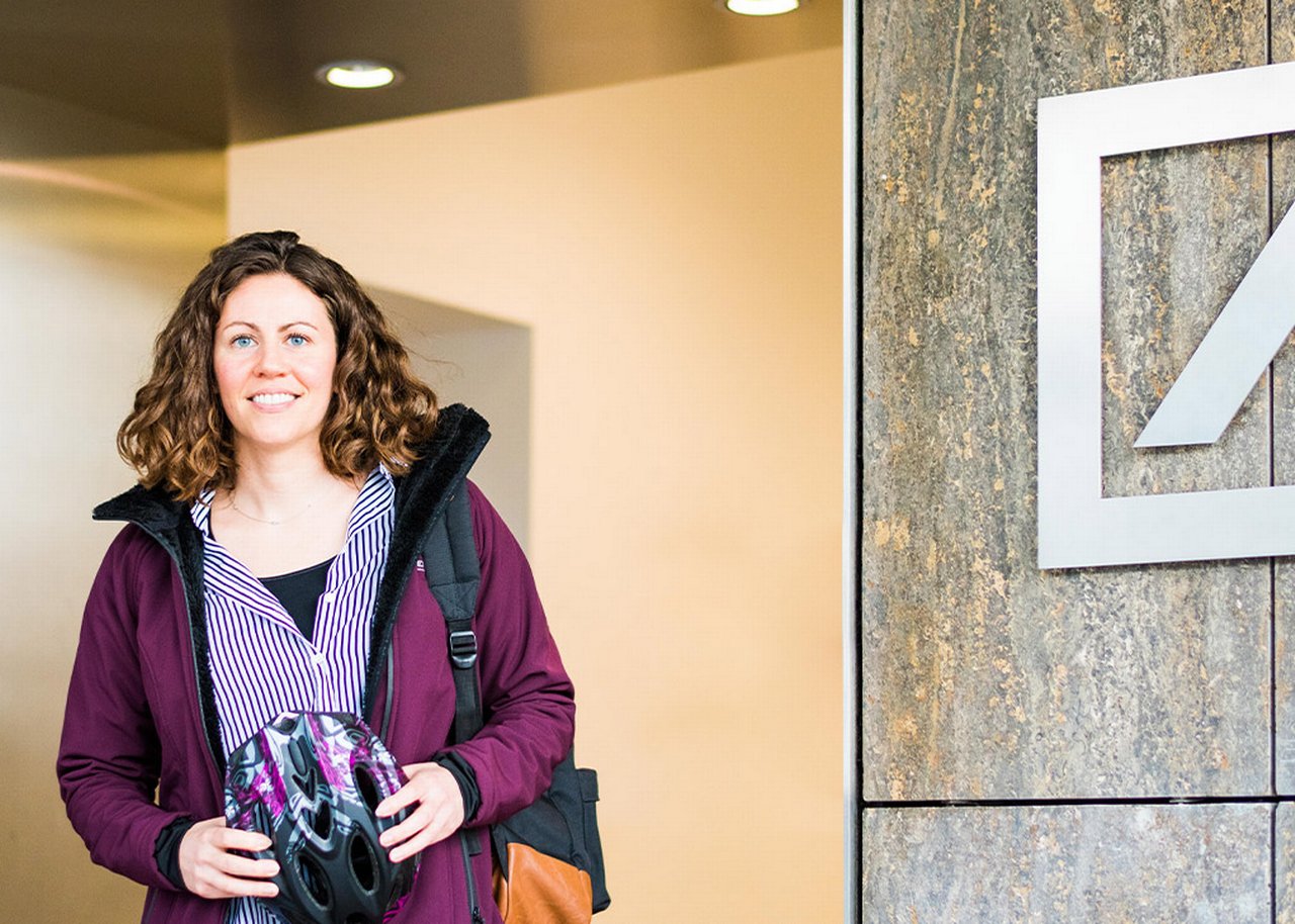 Erin with a bike helmet in front of a Deutsche bank building
