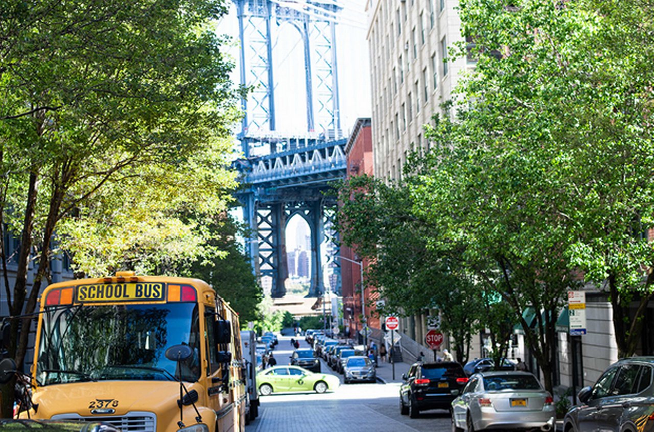 A yellow school bus drives through a city