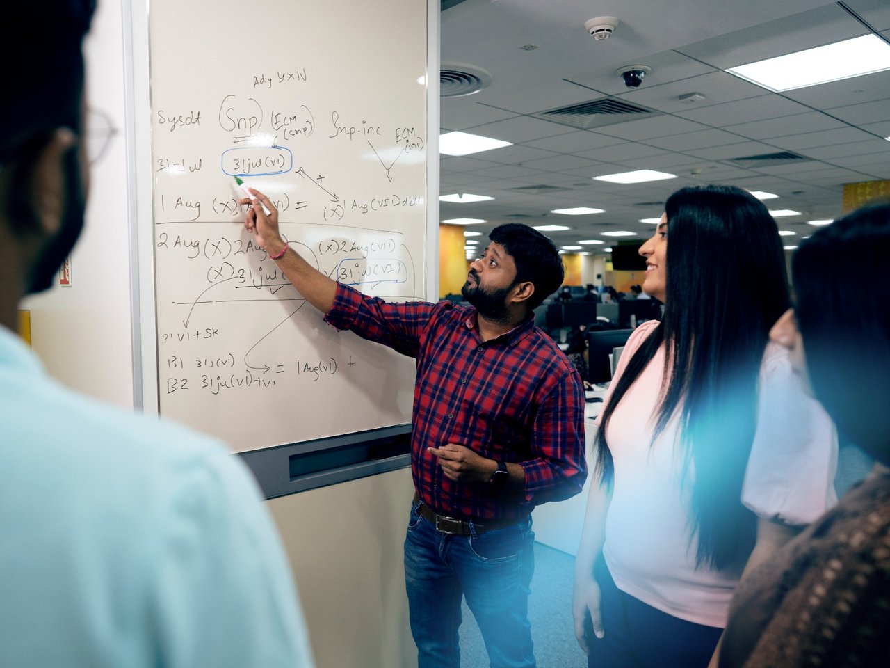 professionals in a meeting in front of a whiteboard