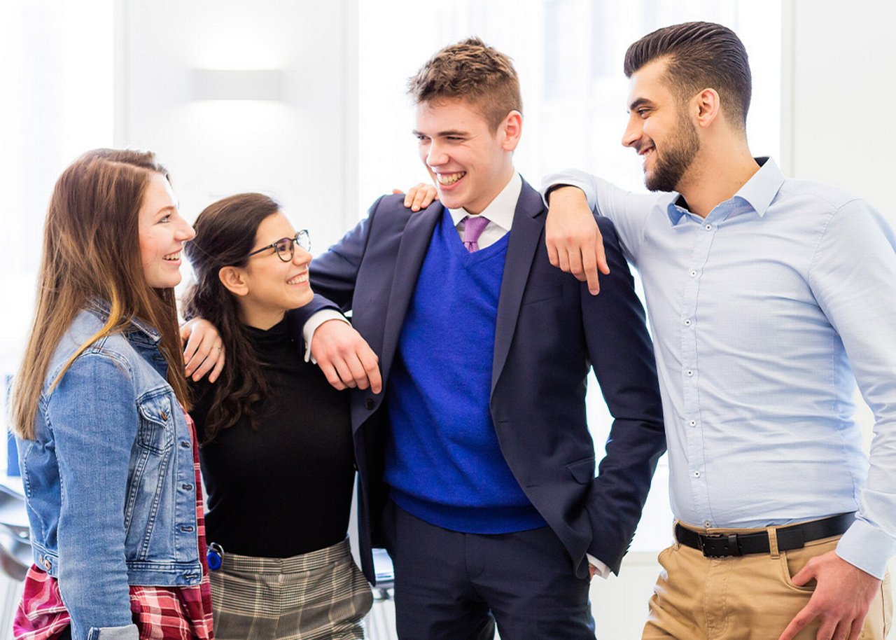 Sofie and her colleagues smiling with their arms on eachothers shoulders