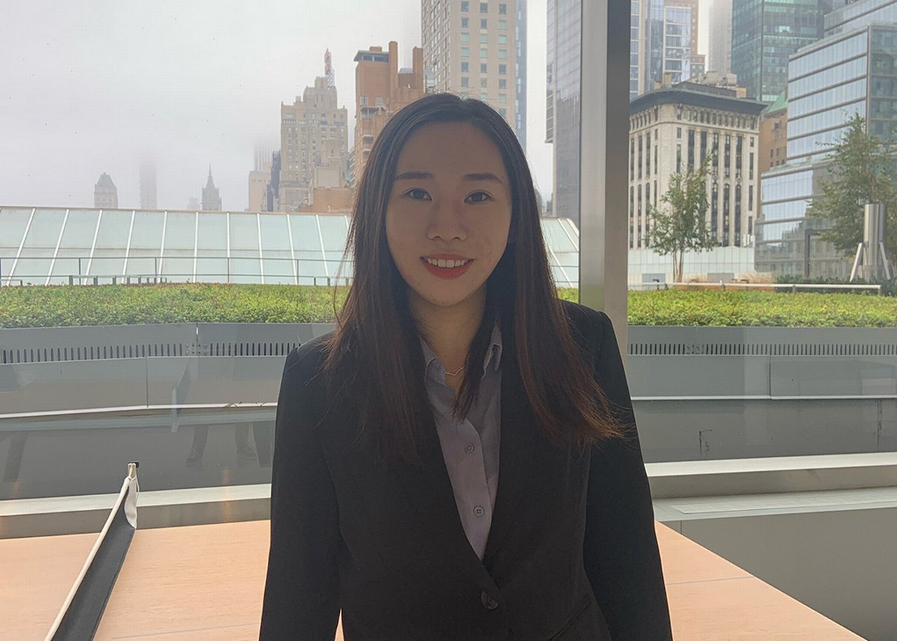 Jiachen smiling, high buildings in background