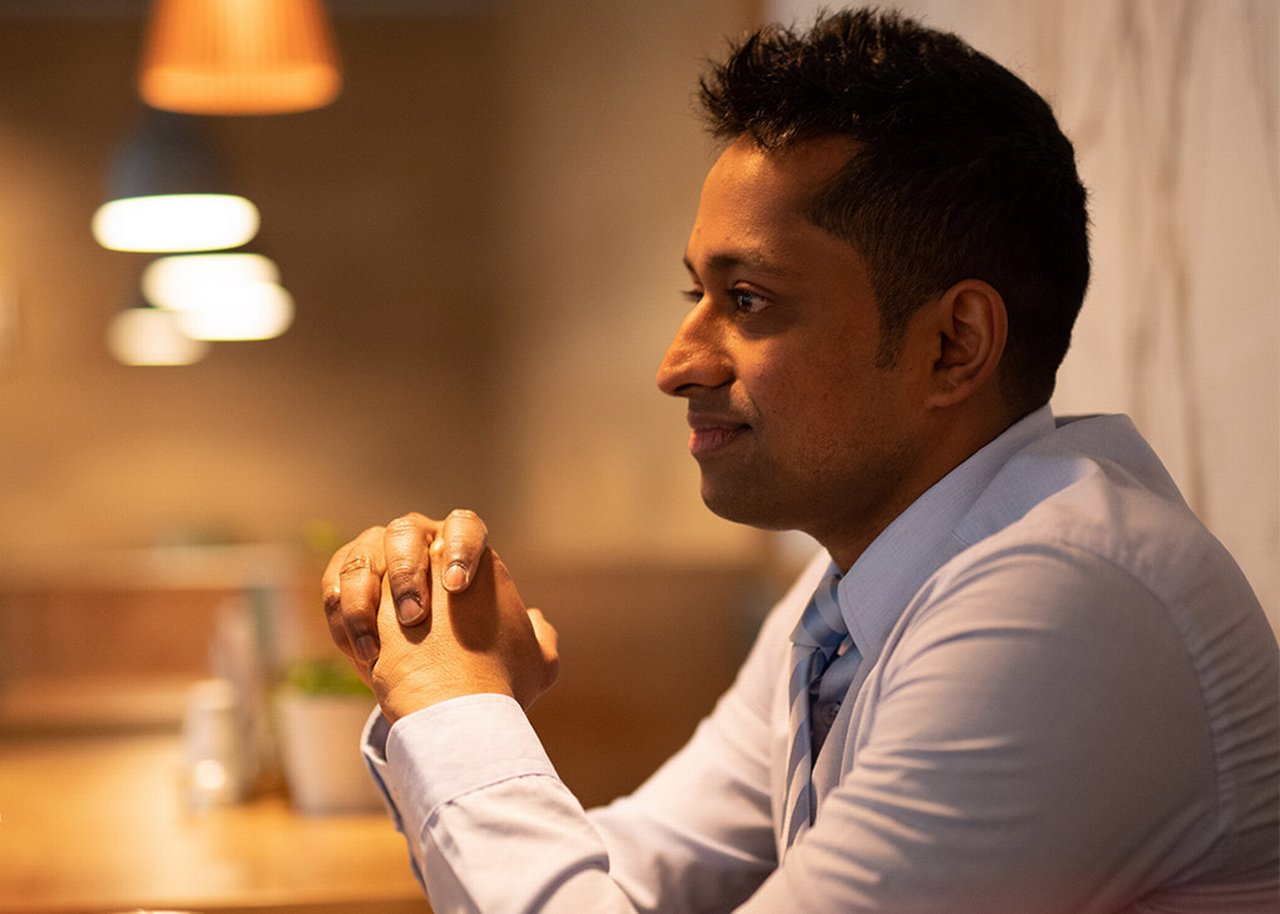 Janagran smiles at a table looking reflective