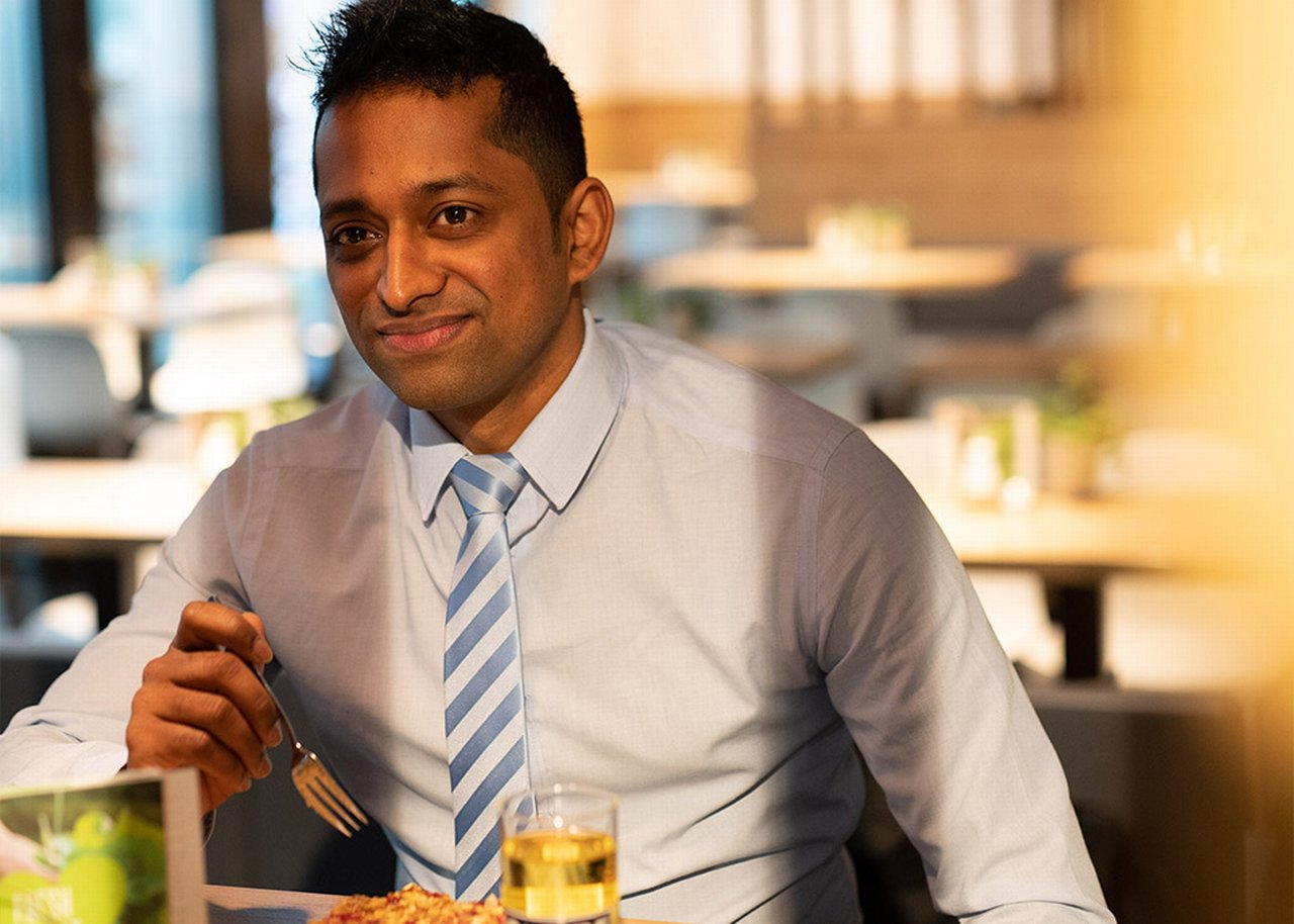 Janagran is sitting at a table eating his lunch