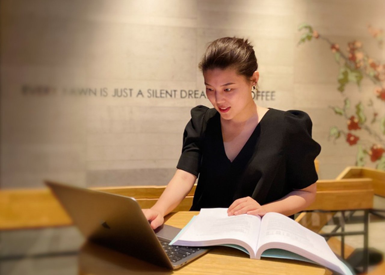 Tori at the table with laptop and book