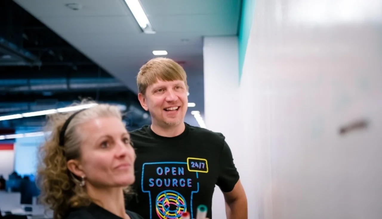 A woman and a man standing in front of a whiteboard