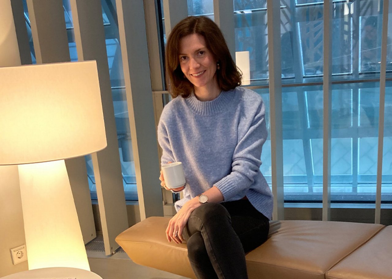 Helen sitzt auf einer Ledercouch, neben ihr eine Stehlampe