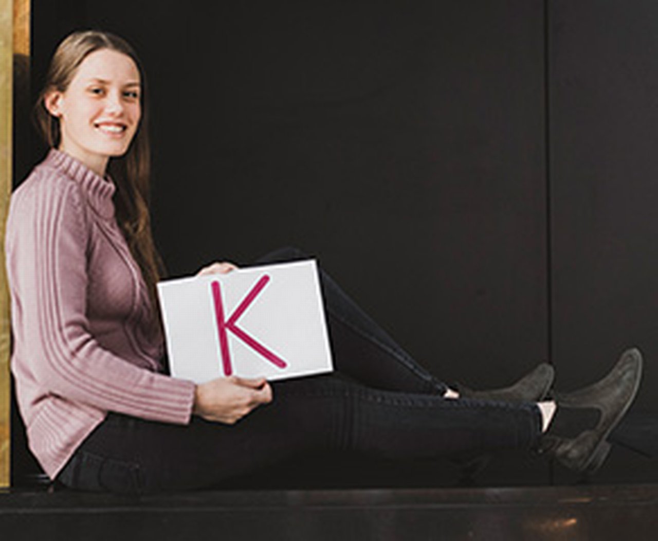 Ein Azubi sitzt mit dem Buchstaben K in der Hand