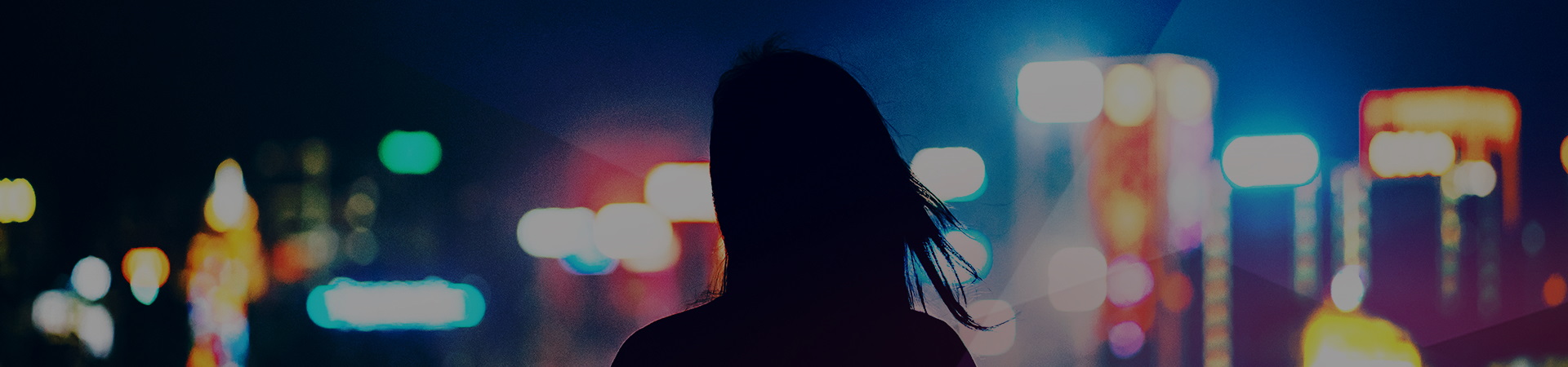 Woman shilouette in front of colorful skyscrapers by night