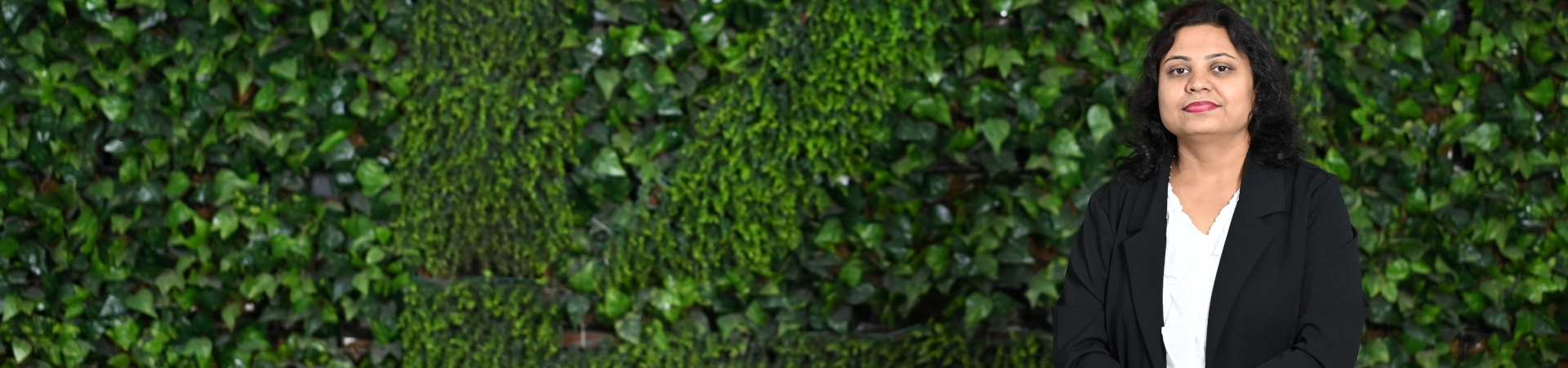 Woman stands infront of the green bushes