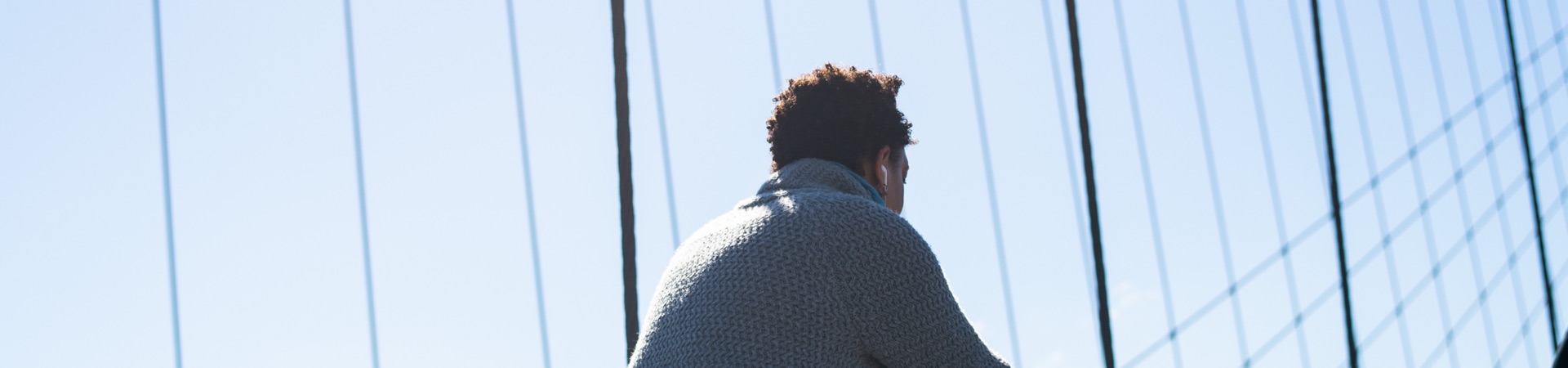 A man is showing his back to the camera on a bridge.