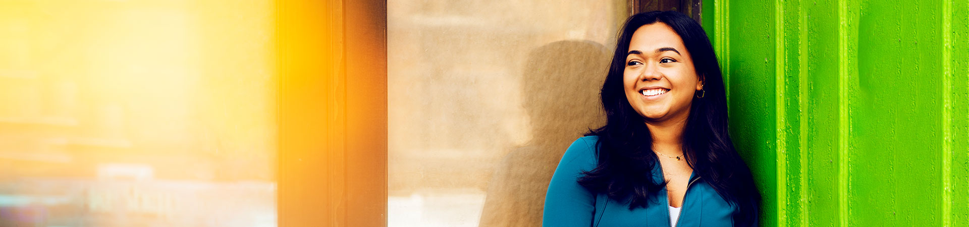 Camila smiles in front of a colorful wall