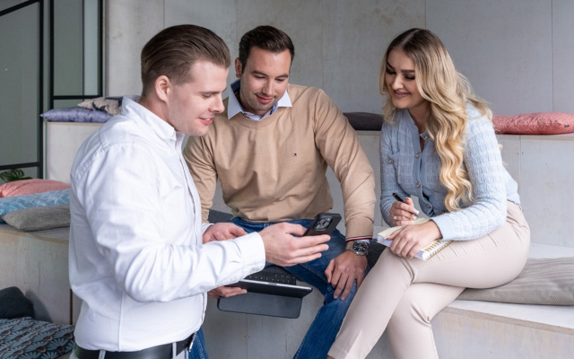 Drei Personen die schauen auf ein Mobiltelefon