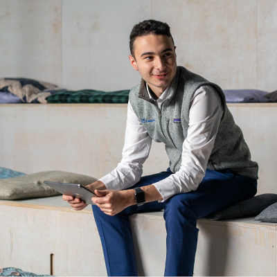 Mann sitzt mit dem Tablett und Lächelt